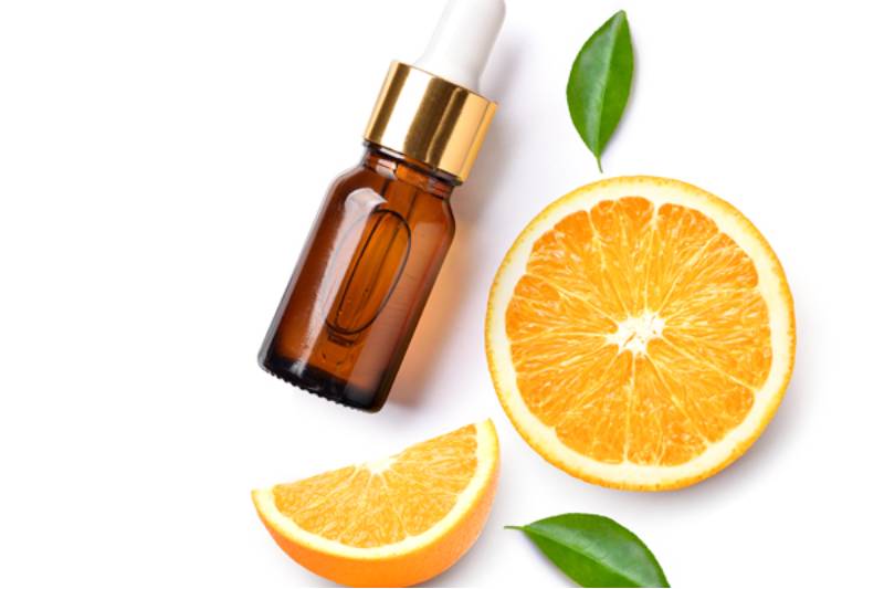 orange fruit, glass bottle and few leaves for orange essential oils